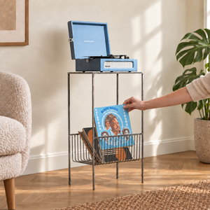 Hand selecting a blue LP sleeve from the lower wire basket of an Atelier Article raw steel record player stand
