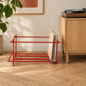 Atelier Article Red Sticks red steel vinyl record crate holding LPs beside an oak cabinet and turntable