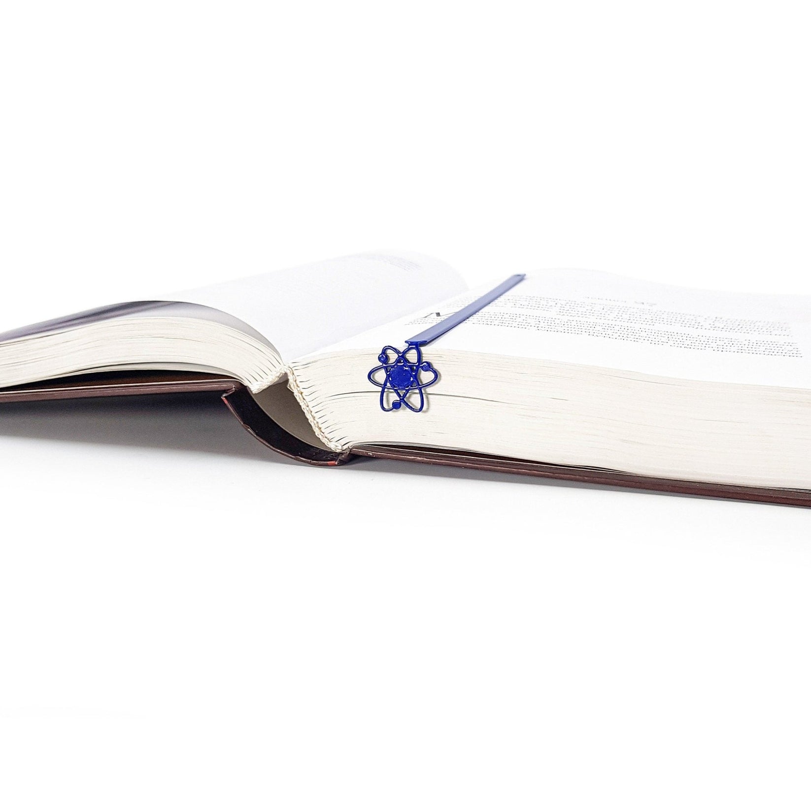 Atom metal bookmark in blue marking a page in an open book