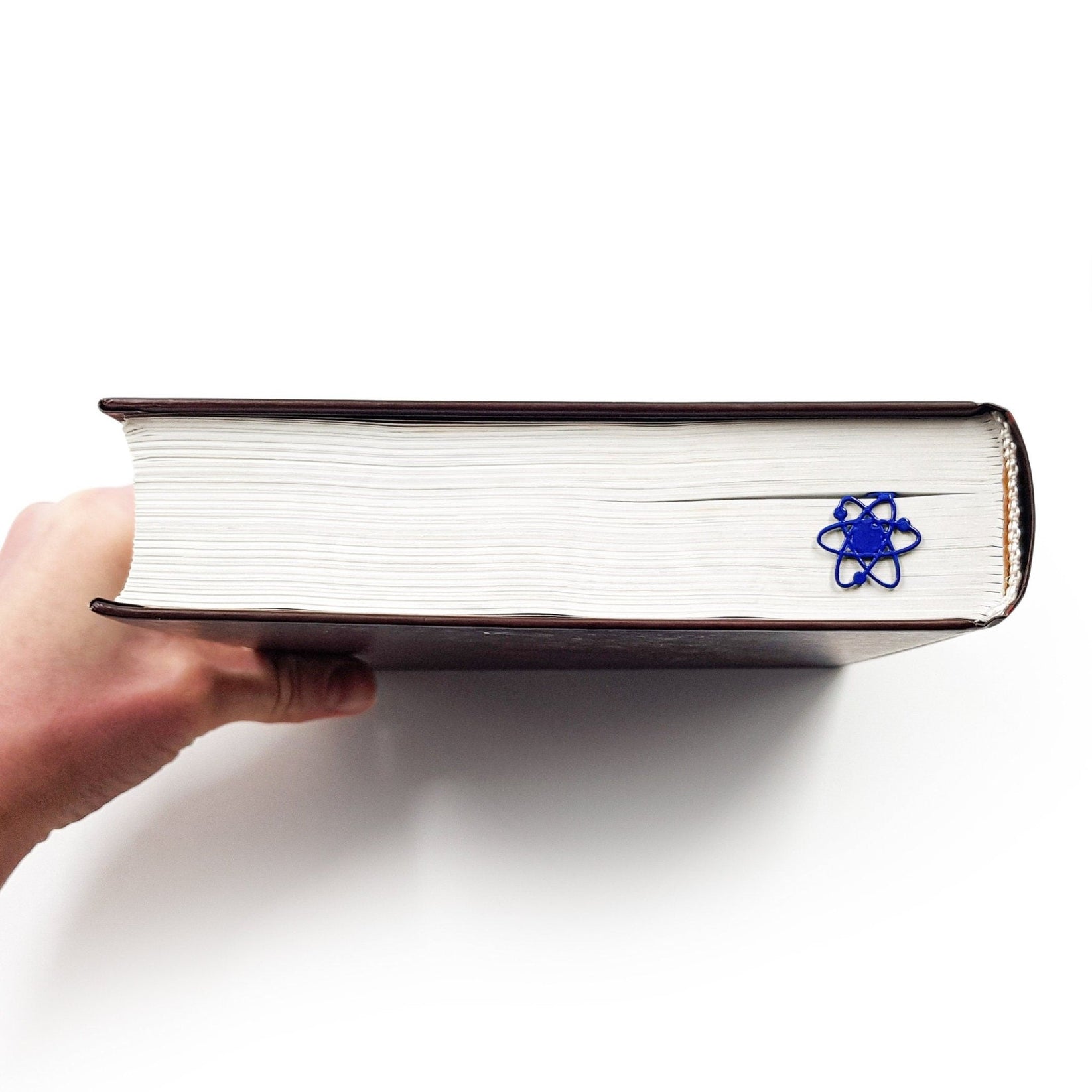 Atom metal bookmark in blue in a closed book, only its top showing above the pages