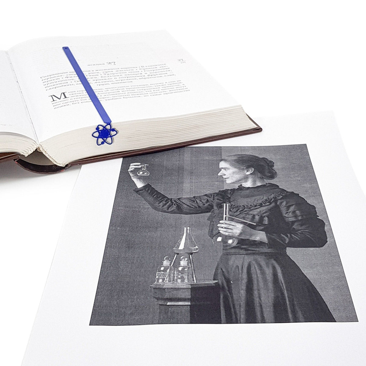 Atom metal bookmark marking a page in an illustrated book