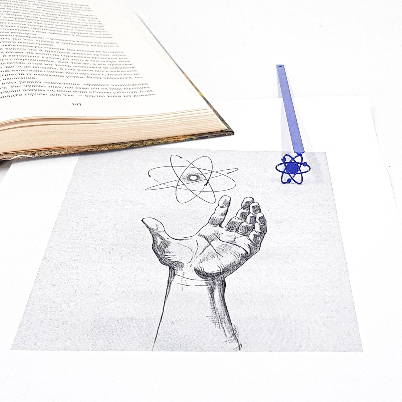 Atom metal bookmark placed on a colour illustration