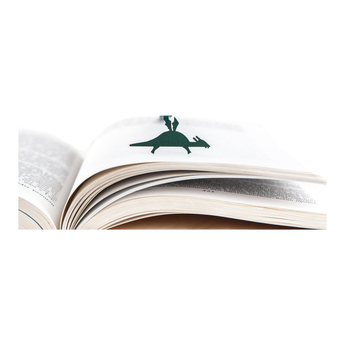 Baby Dinosaur metal bookmark in green resting on the pages of an open book