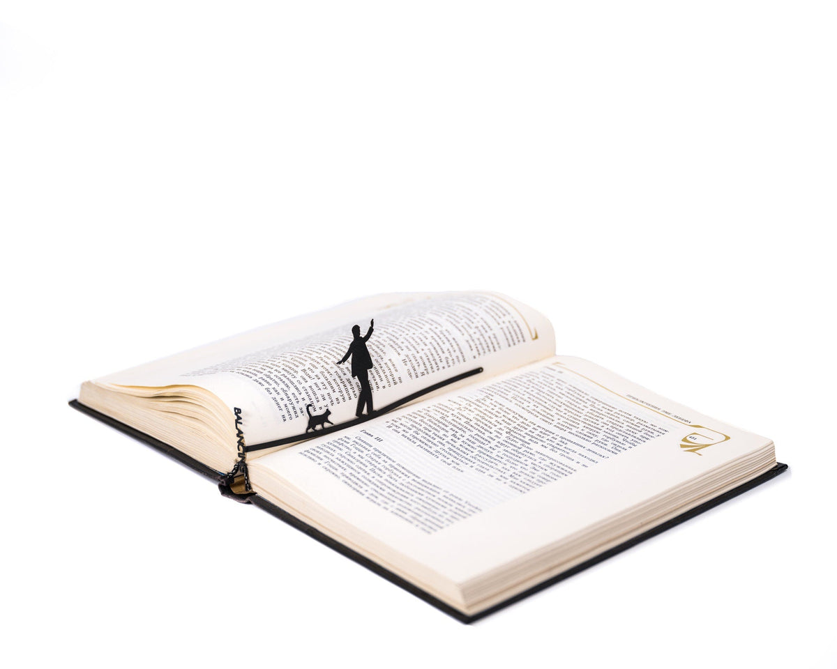 Balancing Act metal bookmark resting on the pages of an open book