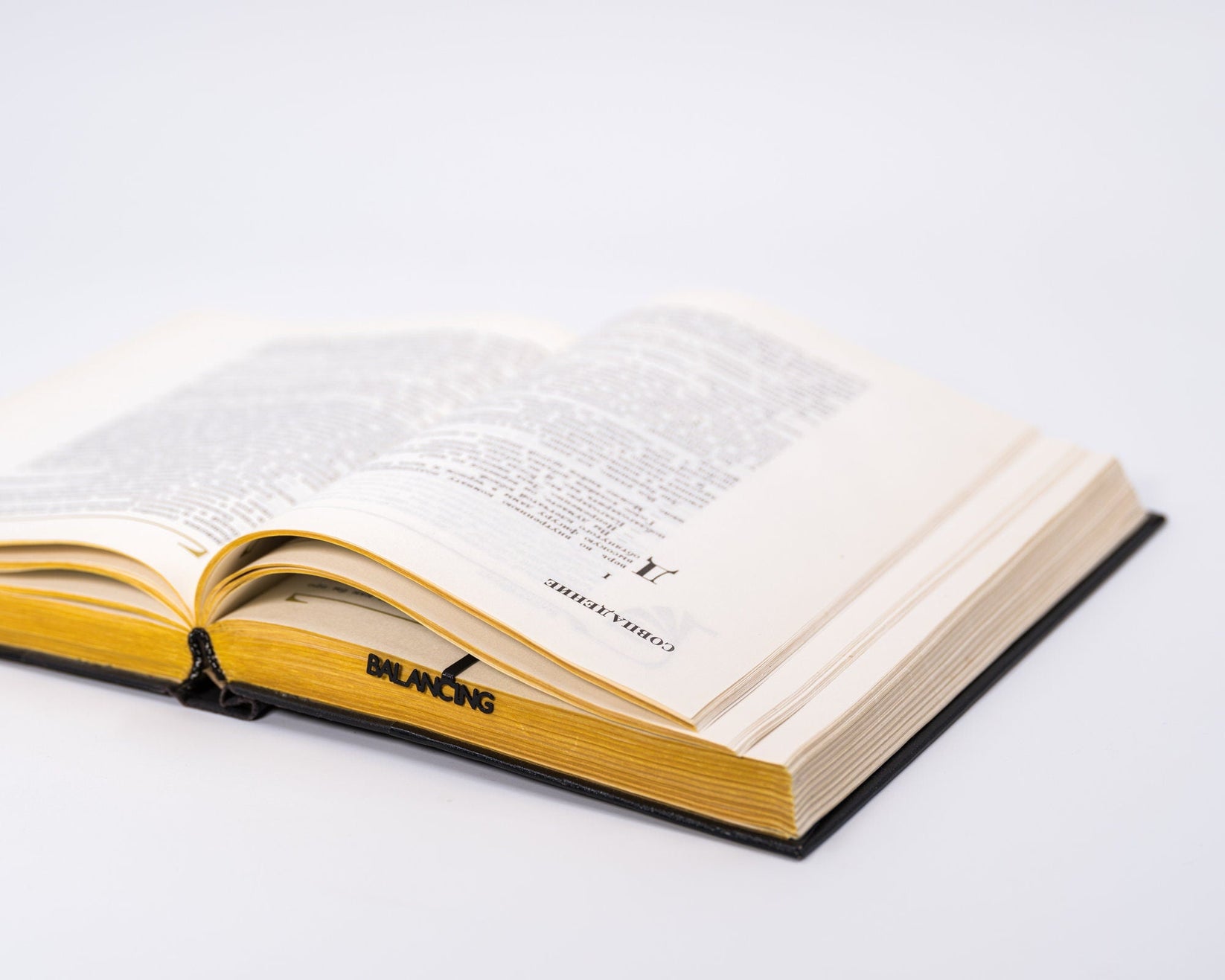 Balancing Act metal bookmark set into the gutter of an open book