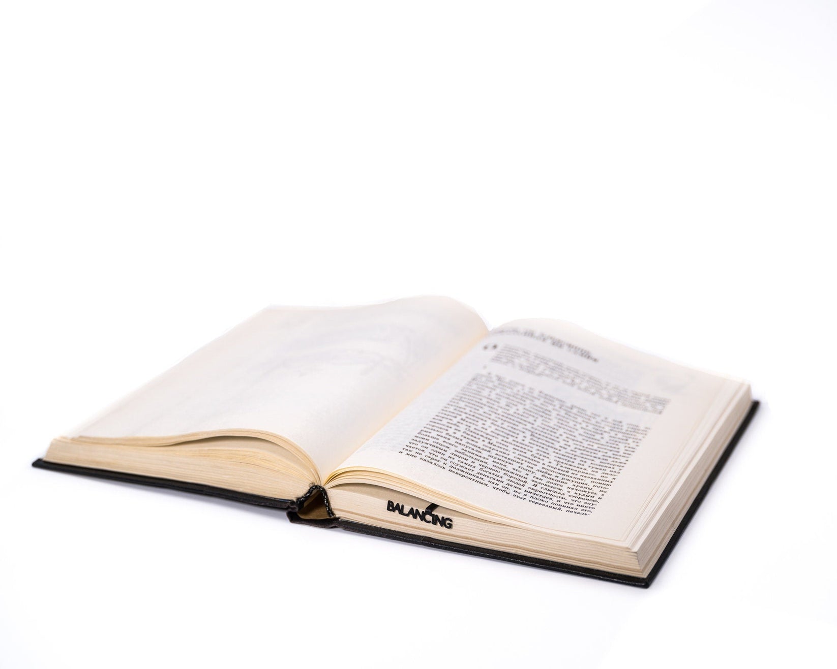 Balancing Act metal bookmark lying across the pages of an open book