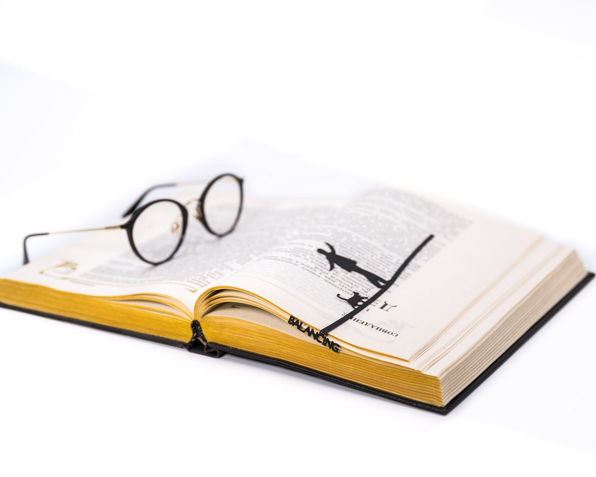 Balancing Act metal bookmark resting on the pages of an open book, view 5