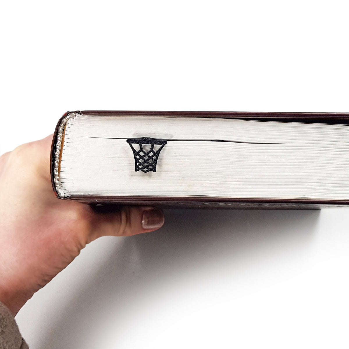 Basketball metal bookmark in a closed book, only its top showing above the pages