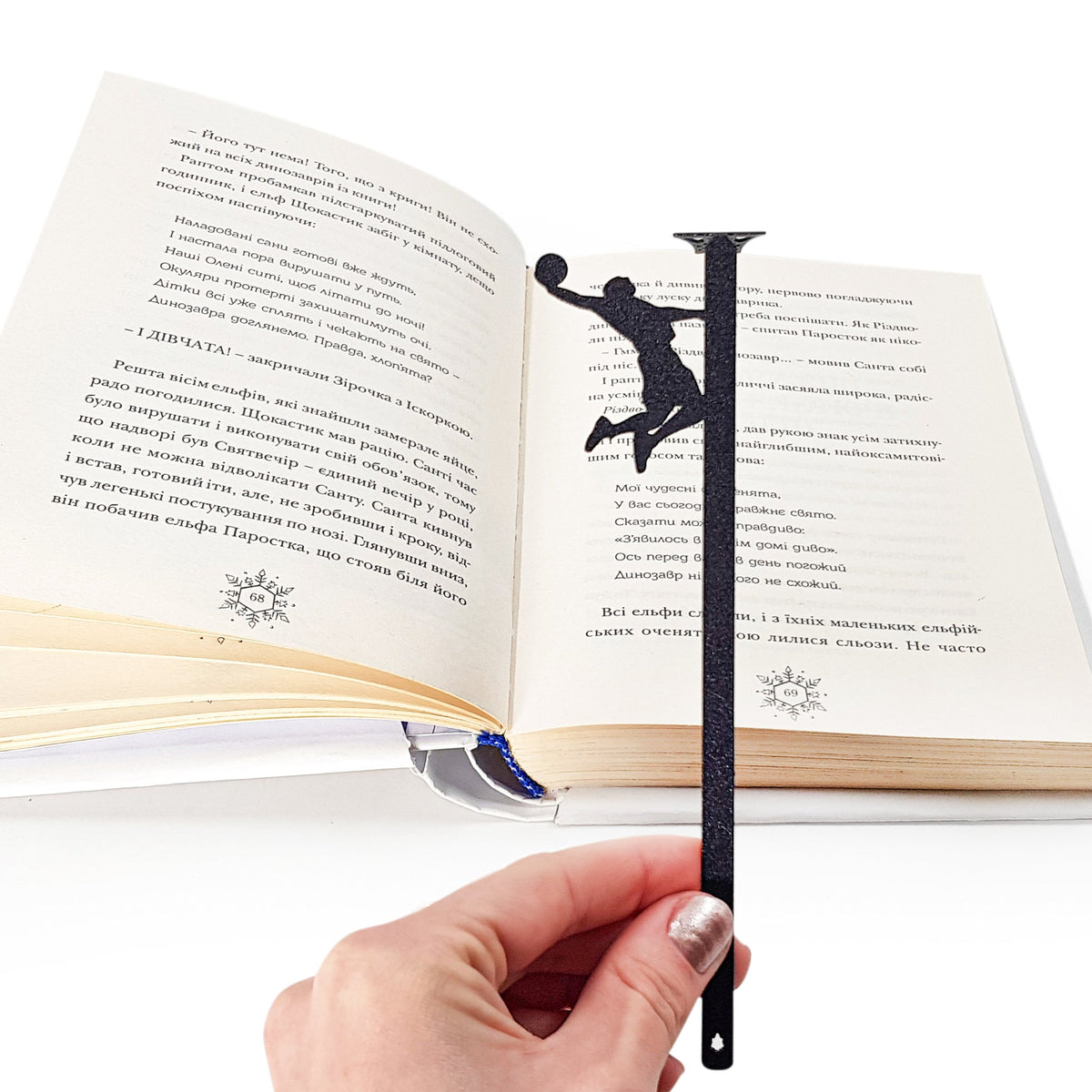 Basketball metal bookmark held in a hand above an open book