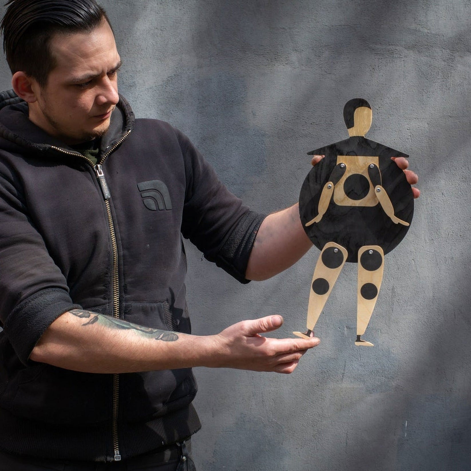 Maker holding the Bauhaus Beetle jumping jack puppet upright, showing the full jointed figure