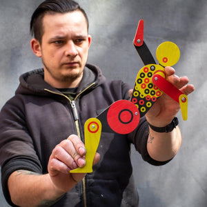 Maker posing Bauhaus circle dancer puppet with both hands against grey background 