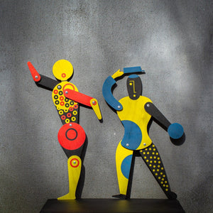 Bauhaus circle dancer puppet with blue and yellow Bauhaus companion puppet on grey wall