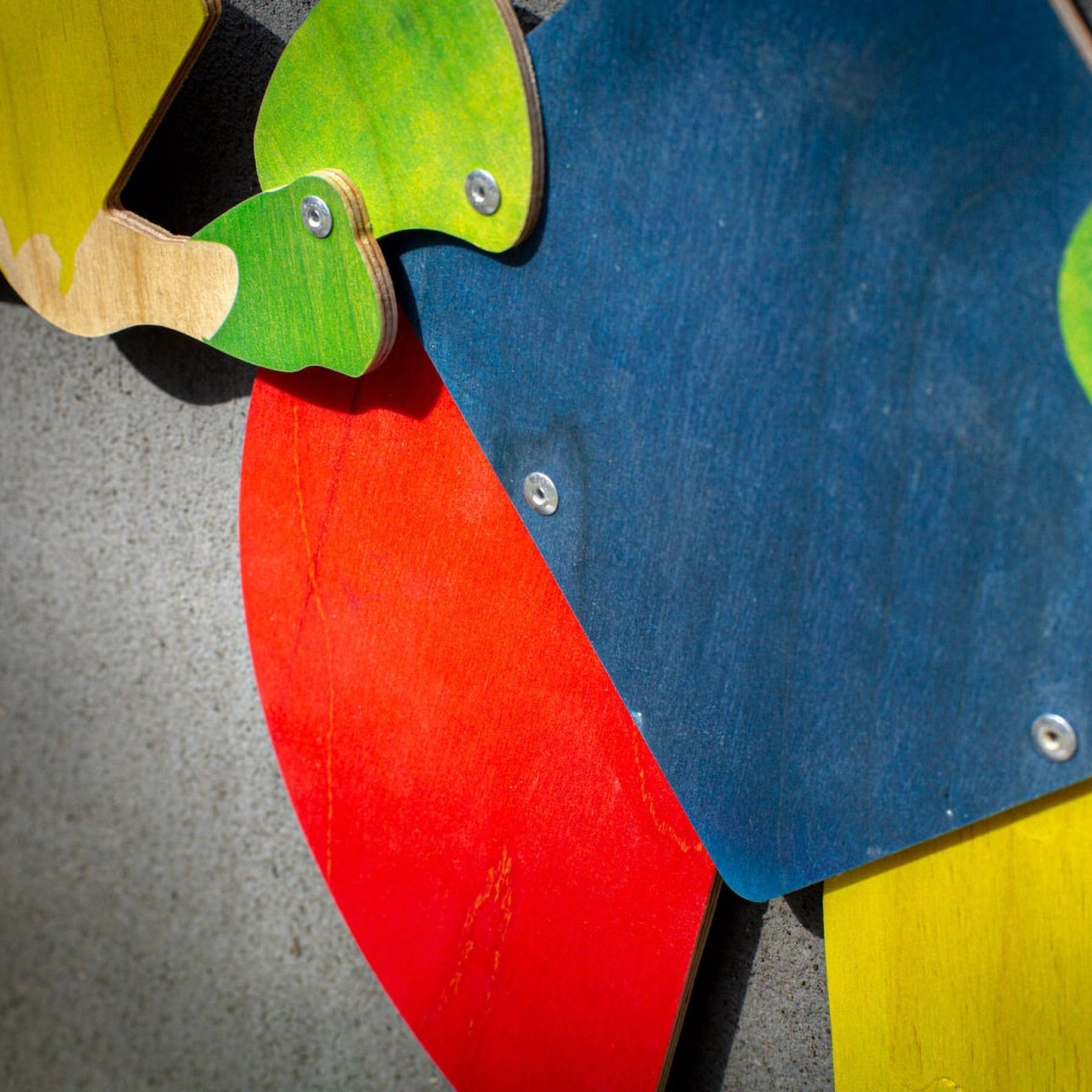 Detail of Bauhaus harlequin puppet — painted plywood surface showing wood grain beneath bold color