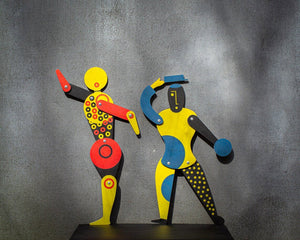 Two Bauhaus jumping jack puppets together — red-yellow and blue-yellow variants
