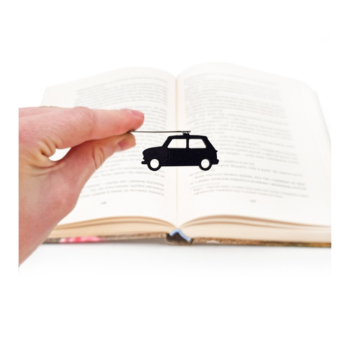 Black Car metal bookmark held in a hand above an open book
