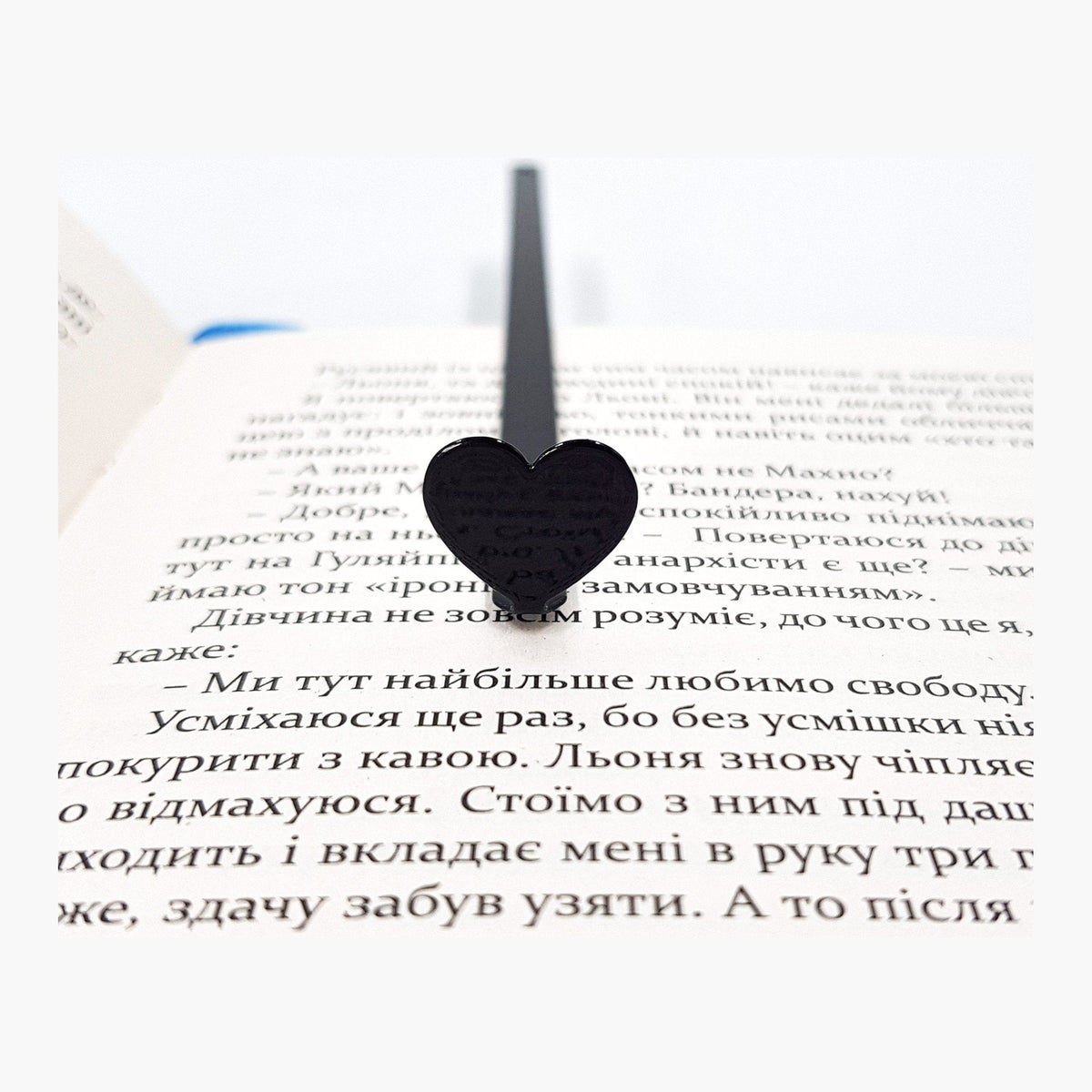 Black Heart metal bookmark resting on the pages of an open book