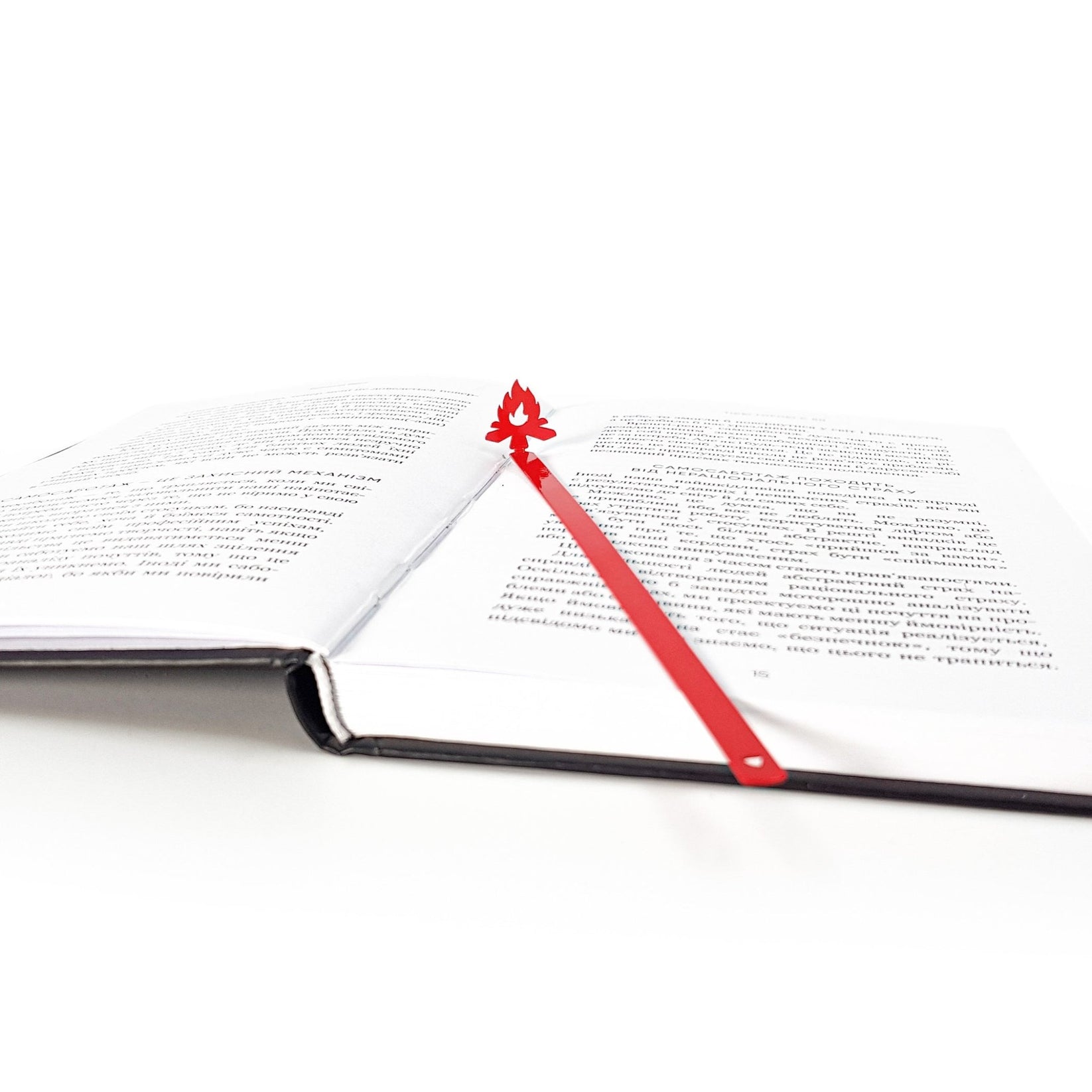 Bonfire metal bookmark in red lying across the pages of an open book