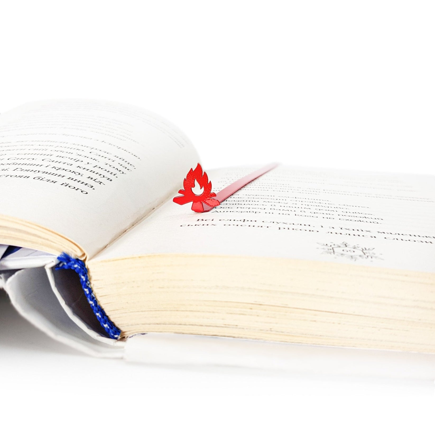 Bonfire metal bookmark in red marking a page in an open book