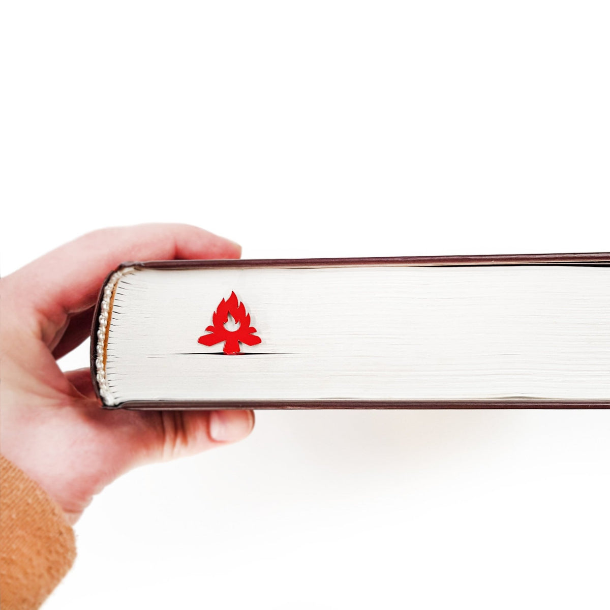 Bonfire metal bookmark in red in a closed book, only its top showing above the pages