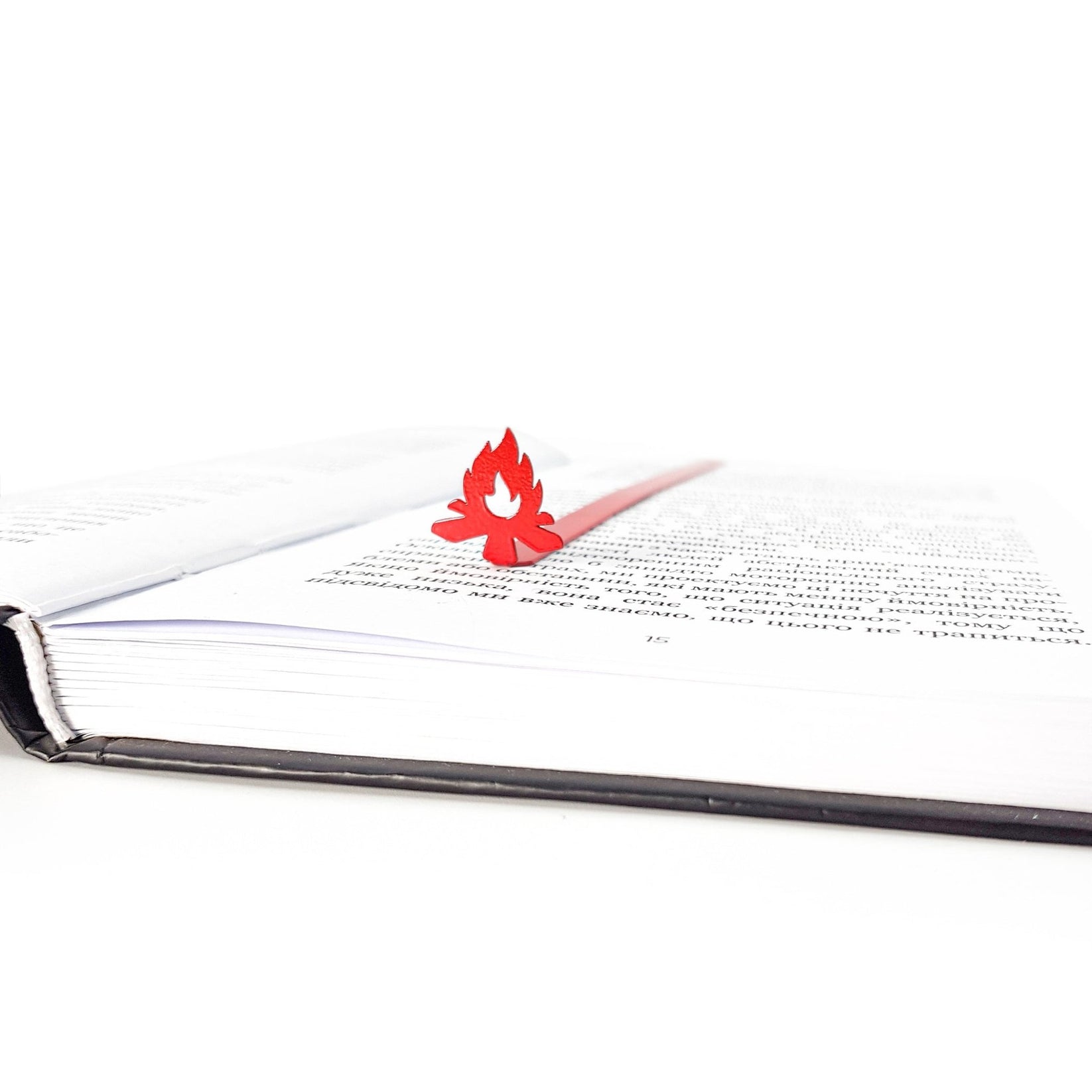 Bonfire metal bookmark in red clipped in a closed book, viewed from the side