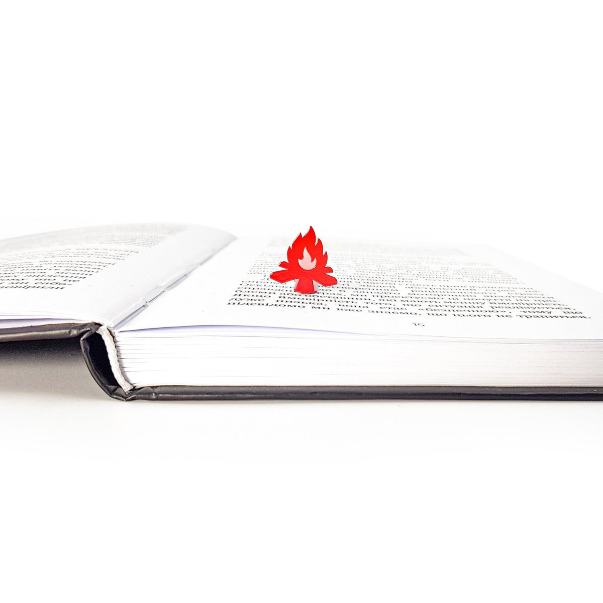 Bonfire metal bookmark in red resting on the pages of an open book, view 5