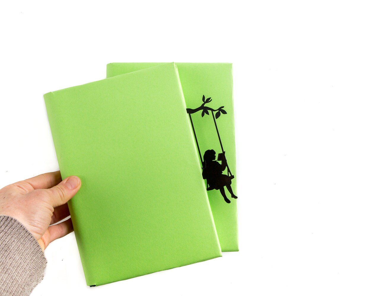 Book Divider Girl on a Swing metal bookmark held in a hand above an open book