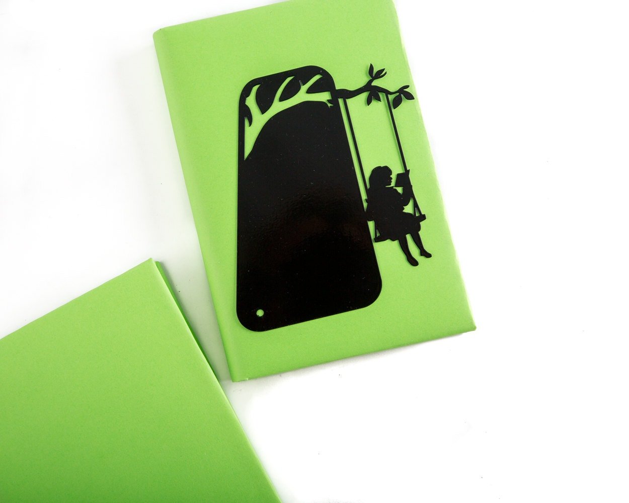 Book Divider Girl on a Swing metal bookmark in a closed book, only its top showing above the pages