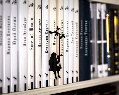Book Divider Girl on a Swing metal bookmark shown with a stack of books