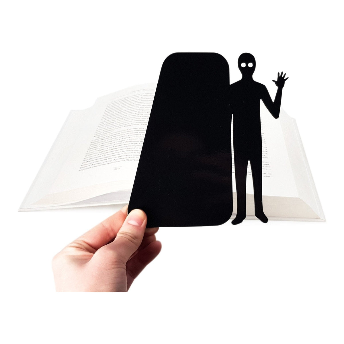 Book Ghost Coming Out metal bookmark held in a hand above an open book