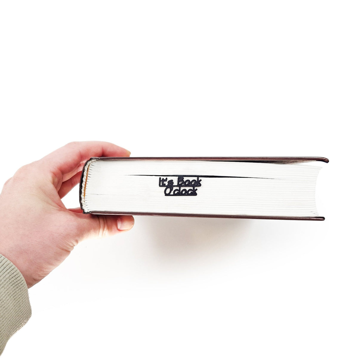 Hand holding a book with 'It's Book O'Clock' text on a white background