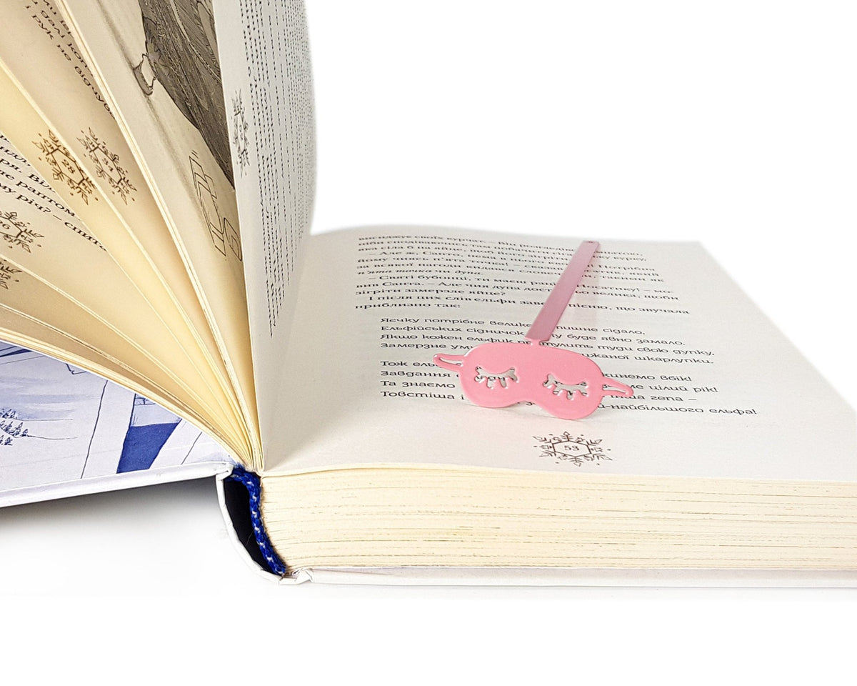 Sleep Mask metal bookmark in red lying across the pages of an open book