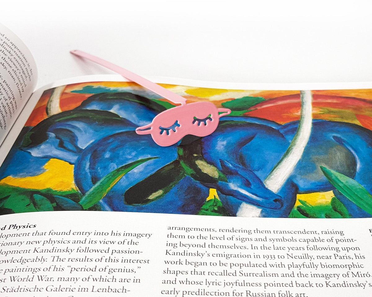 Sleep Mask metal bookmark in red marking a page in an illustrated book