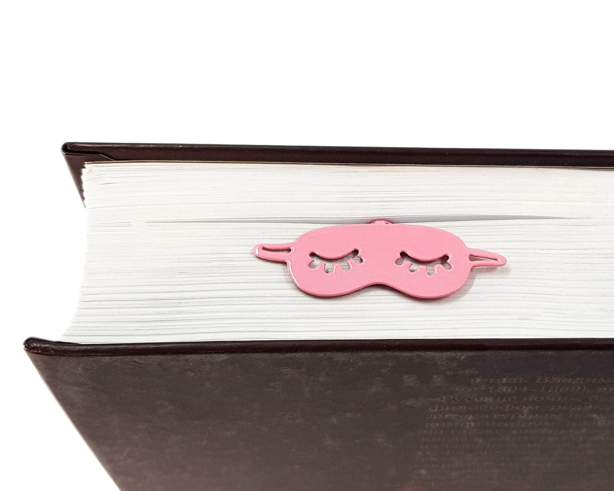 Sleep Mask metal bookmark in red resting on the pages of an open book