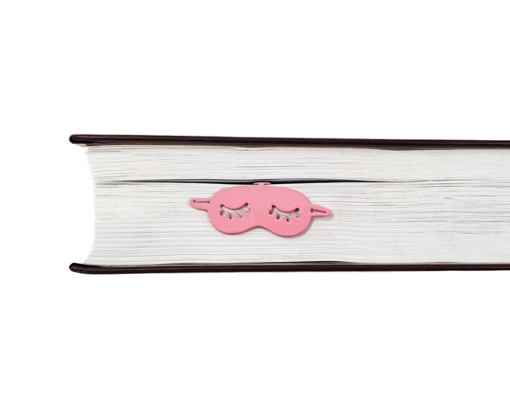 Sleep Mask metal bookmark in red in a closed book, only its top showing above the pages