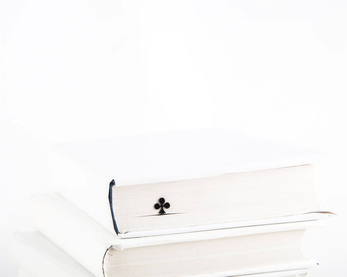 Ace of Clubs metal bookmark in a closed book, only its top showing above the pages