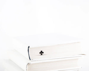Ace of Clubs metal bookmark in a closed book, only its top showing above the pages