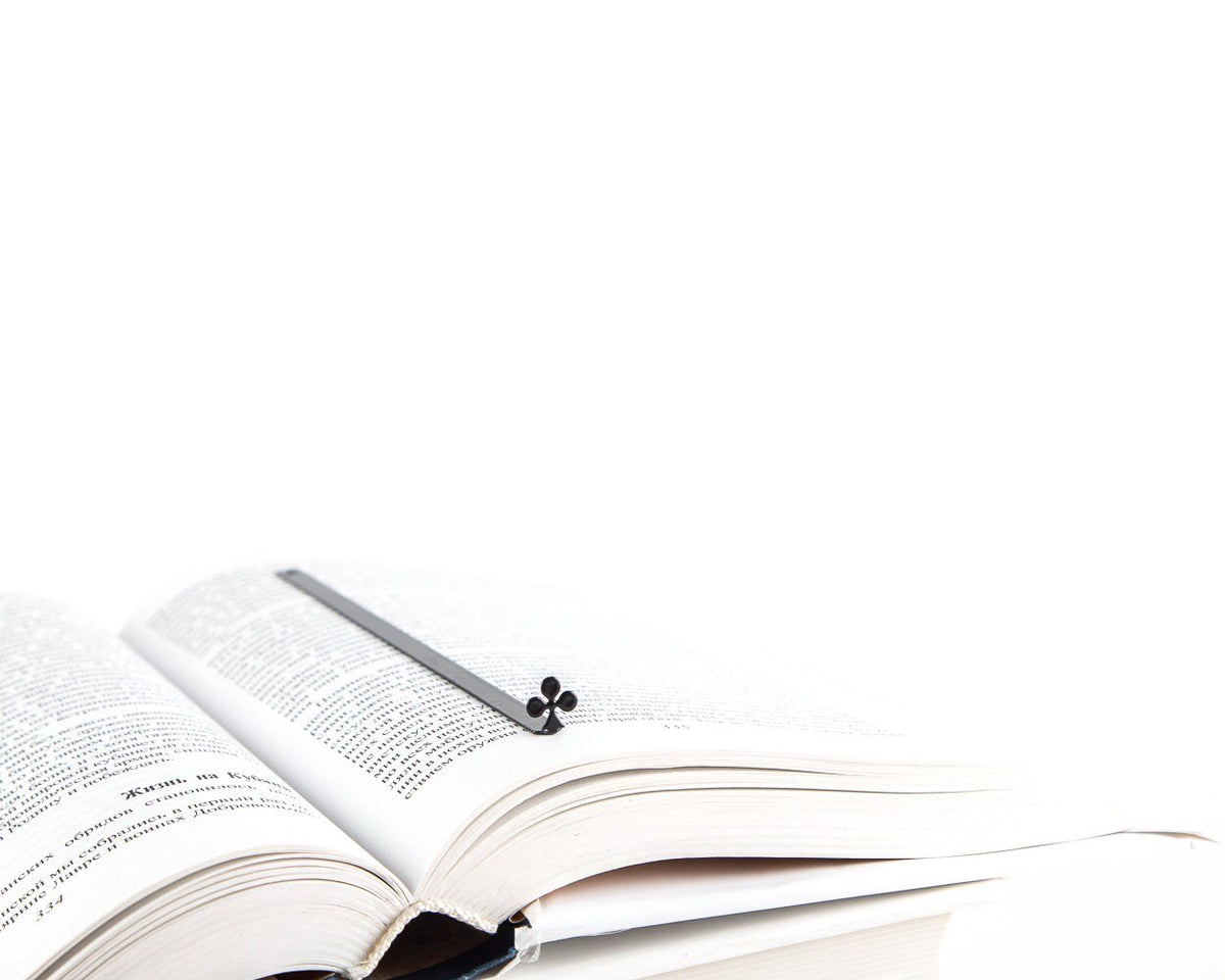 Ace of Clubs metal bookmark resting on the pages of an open book