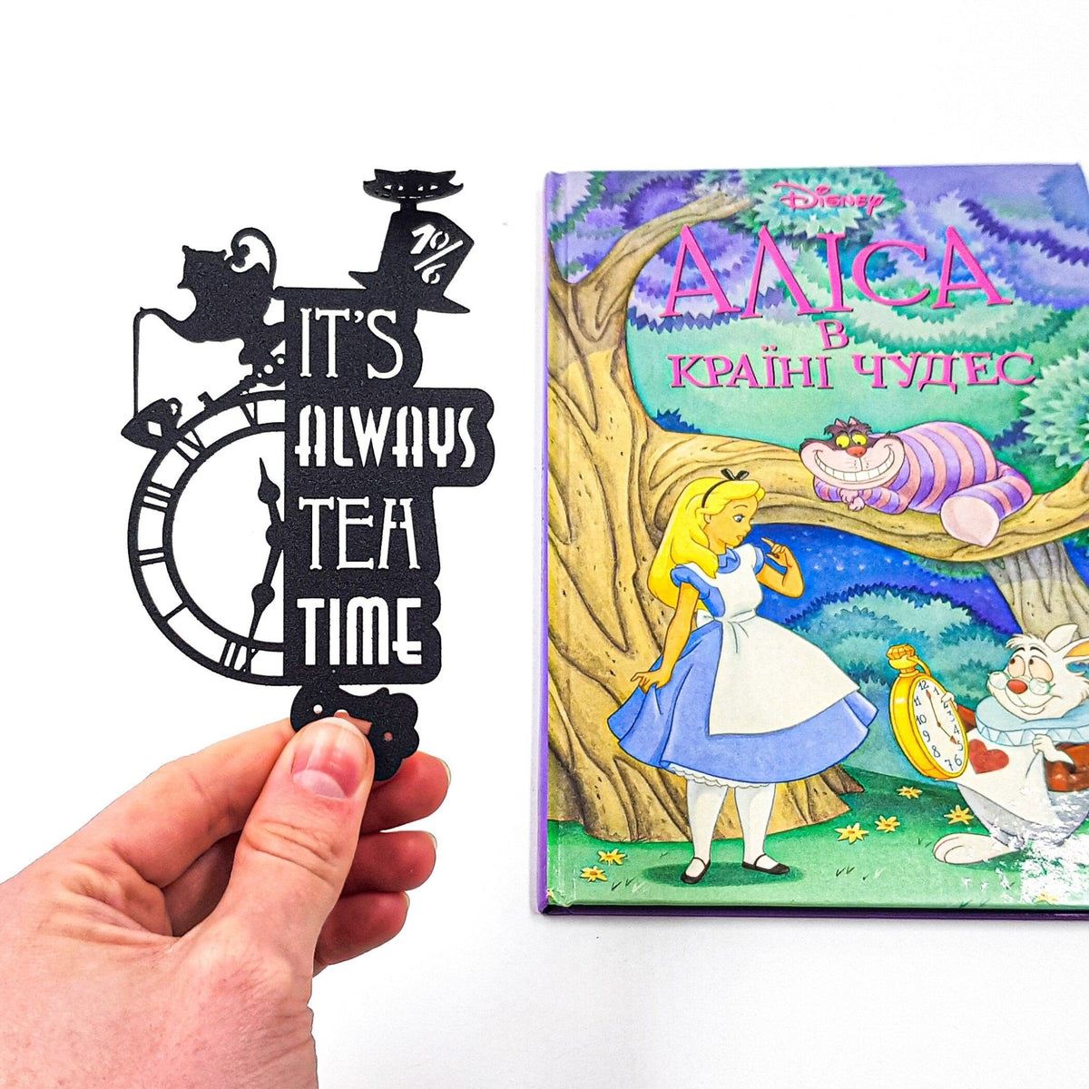 Alice in Wonderland's The Tea Party metal bookmark placed on a colour illustration