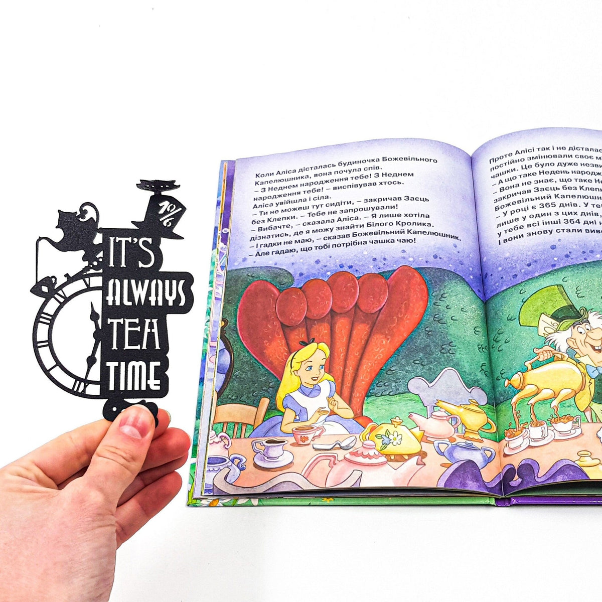 Alice in Wonderland's The Tea Party metal bookmark marking a page in an illustrated book, view 4