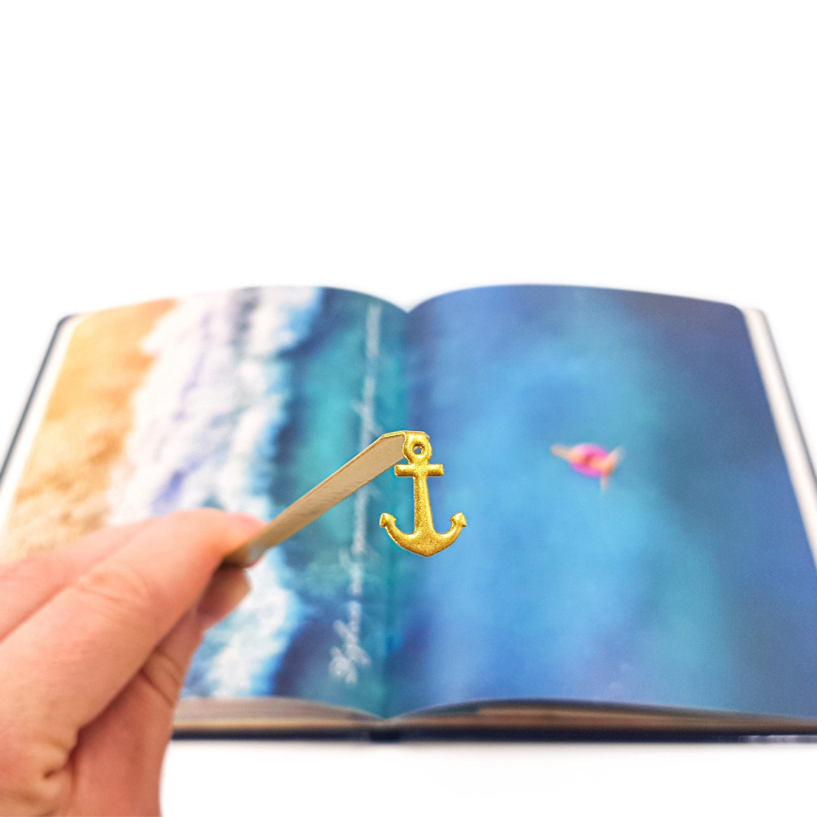 Anchor metal bookmark in gold marking a page in an illustrated book