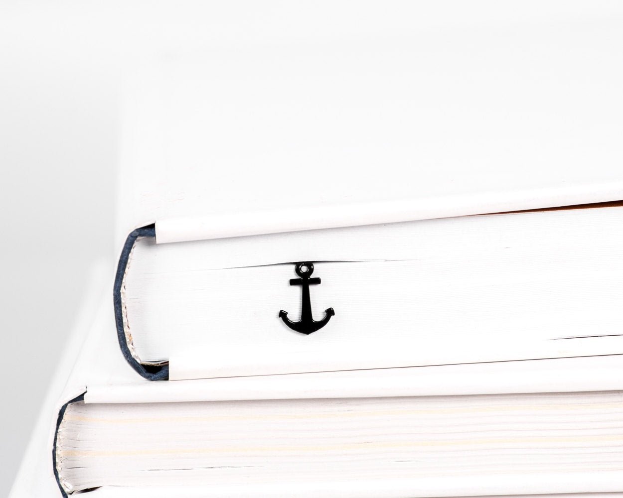 Anchor metal bookmark in a closed book, only its top showing above the pages