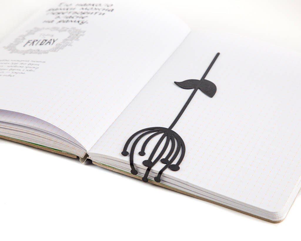 Anethum metal bookmark marking a page in a notebook