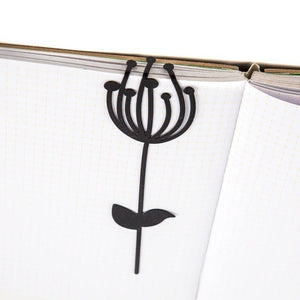 Anethum metal bookmark resting on the pages of an open book