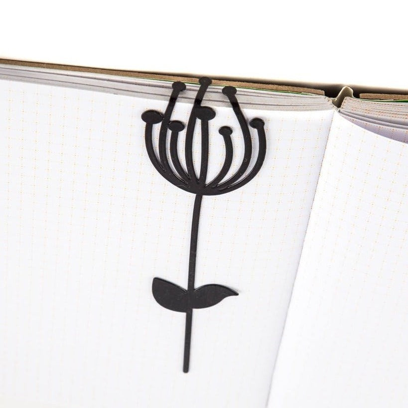 Anethum metal bookmark resting on the pages of an open book