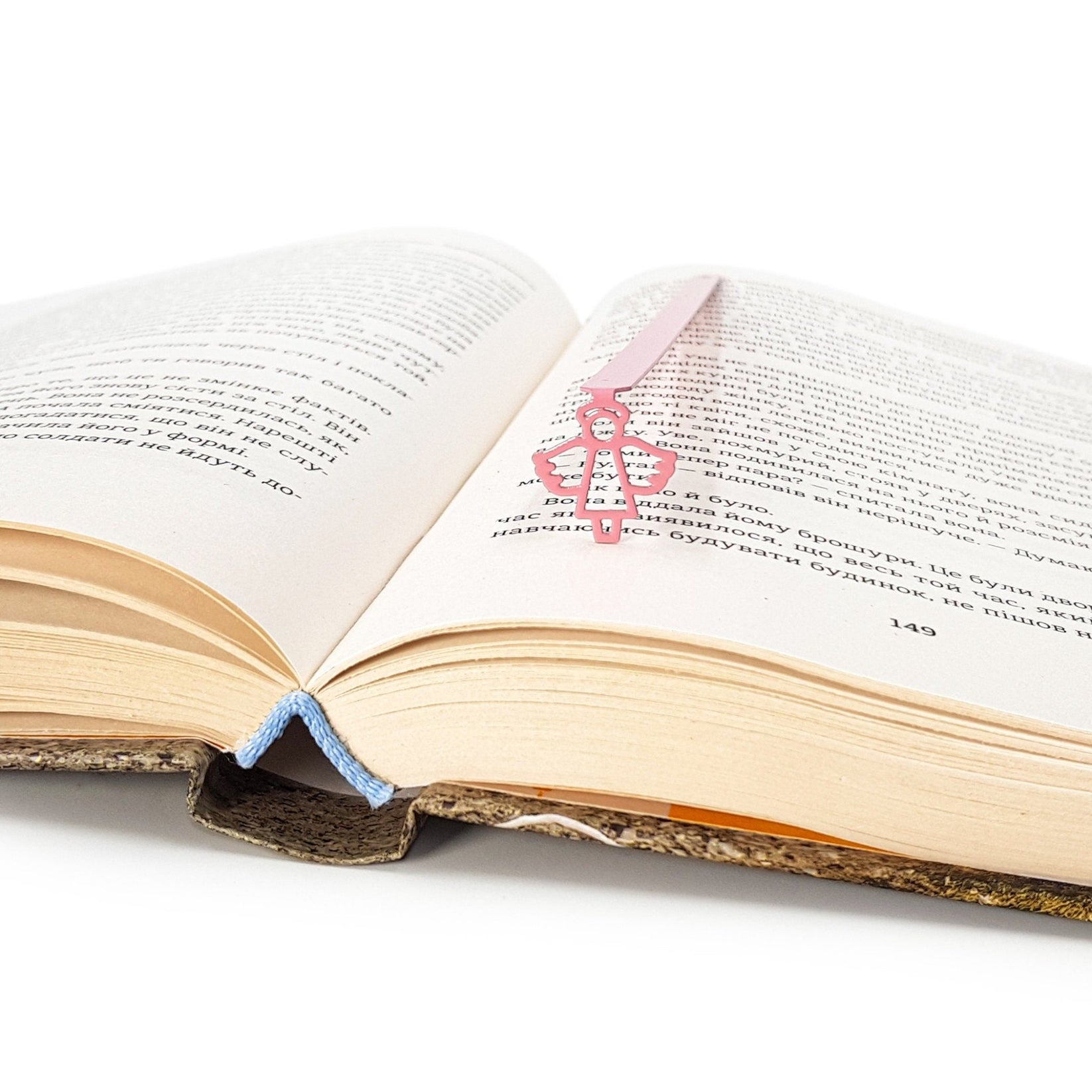 Angel metal bookmark in red resting on the pages of an open book