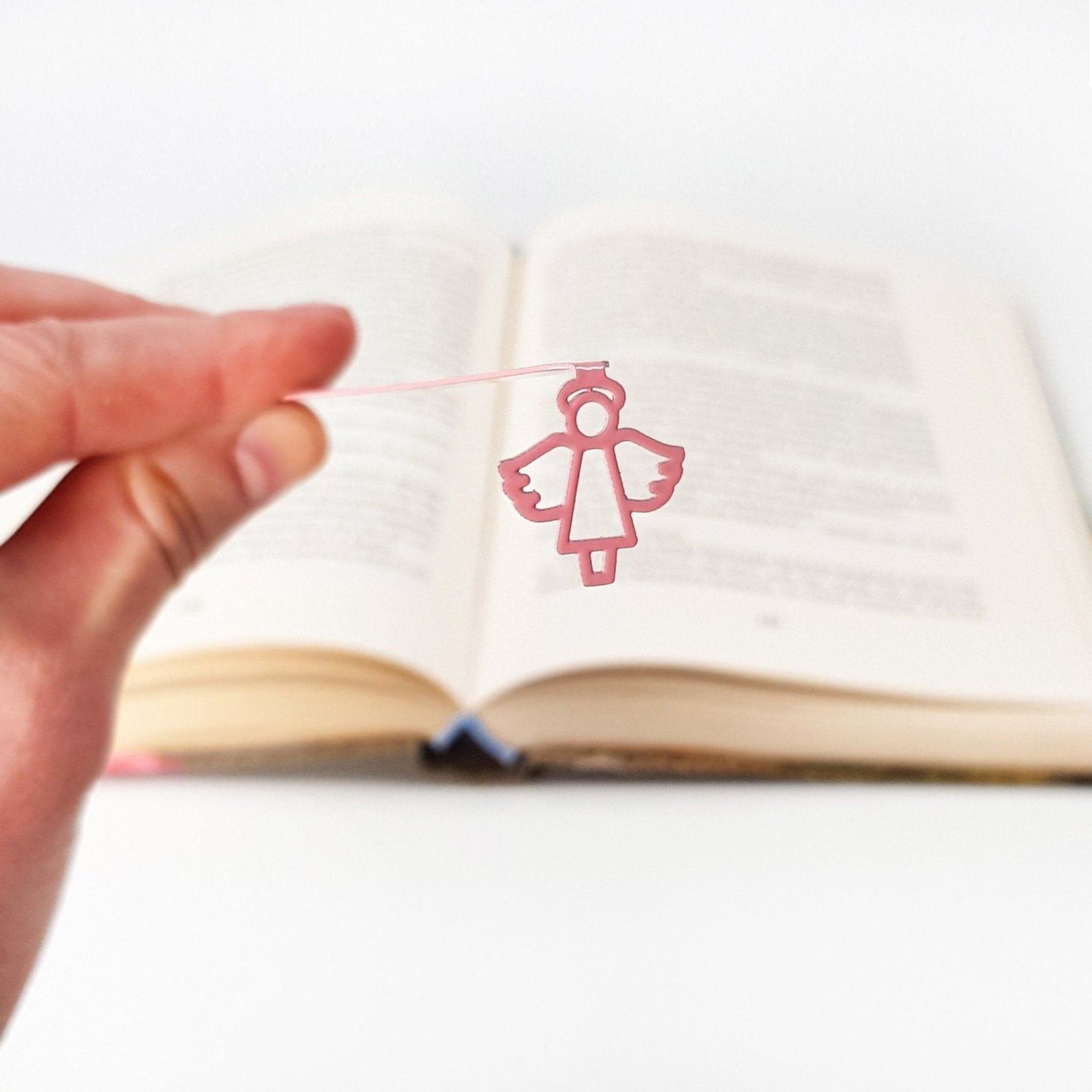 Angel metal bookmark in red held in a hand to show its size