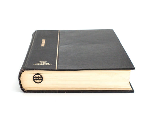 Aquarius metal bookmark in a closed book, only its top showing above the pages