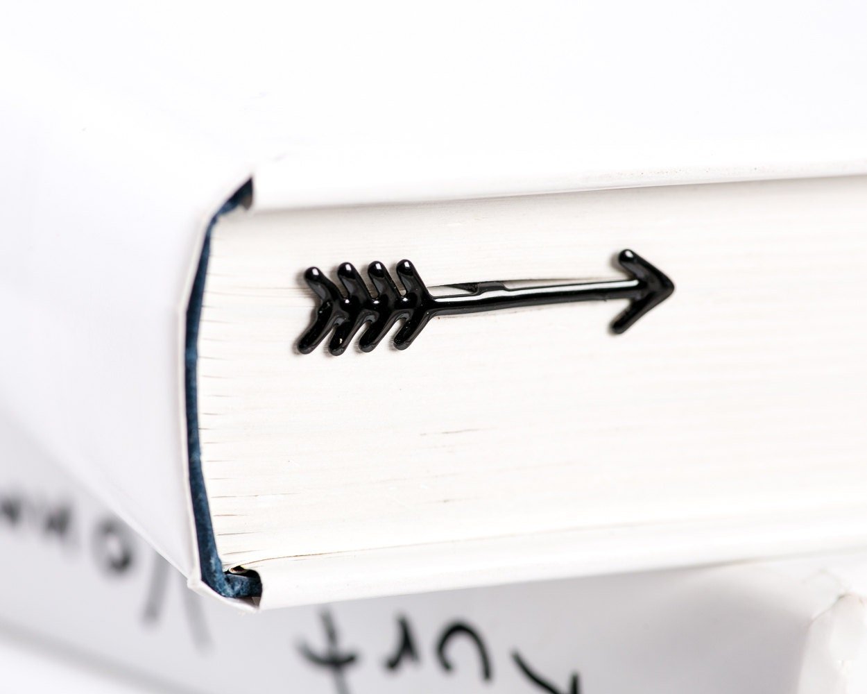 Arrow metal bookmark in a closed book, only its top showing above the pages
