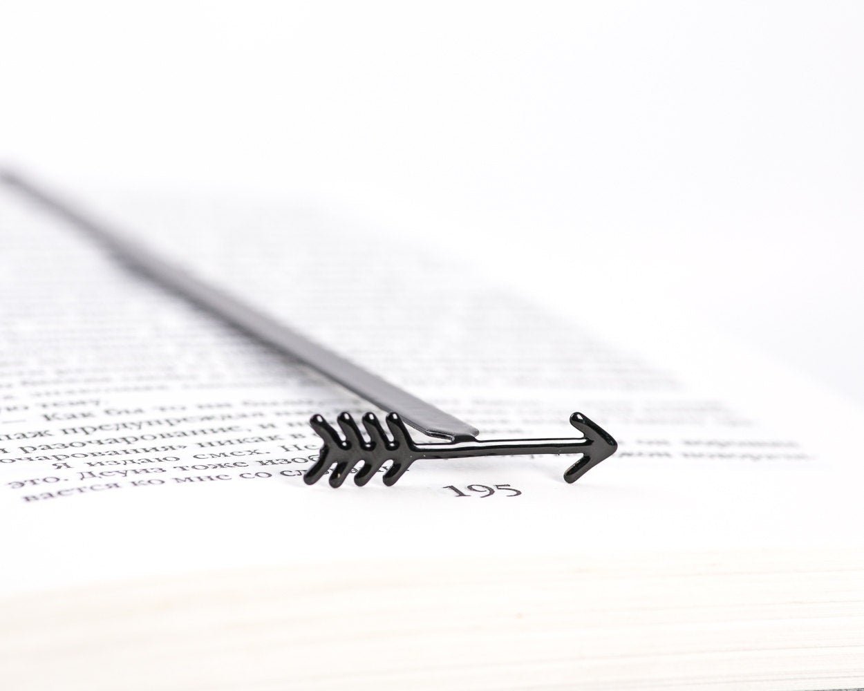 Arrow metal bookmark resting on the pages of an open book