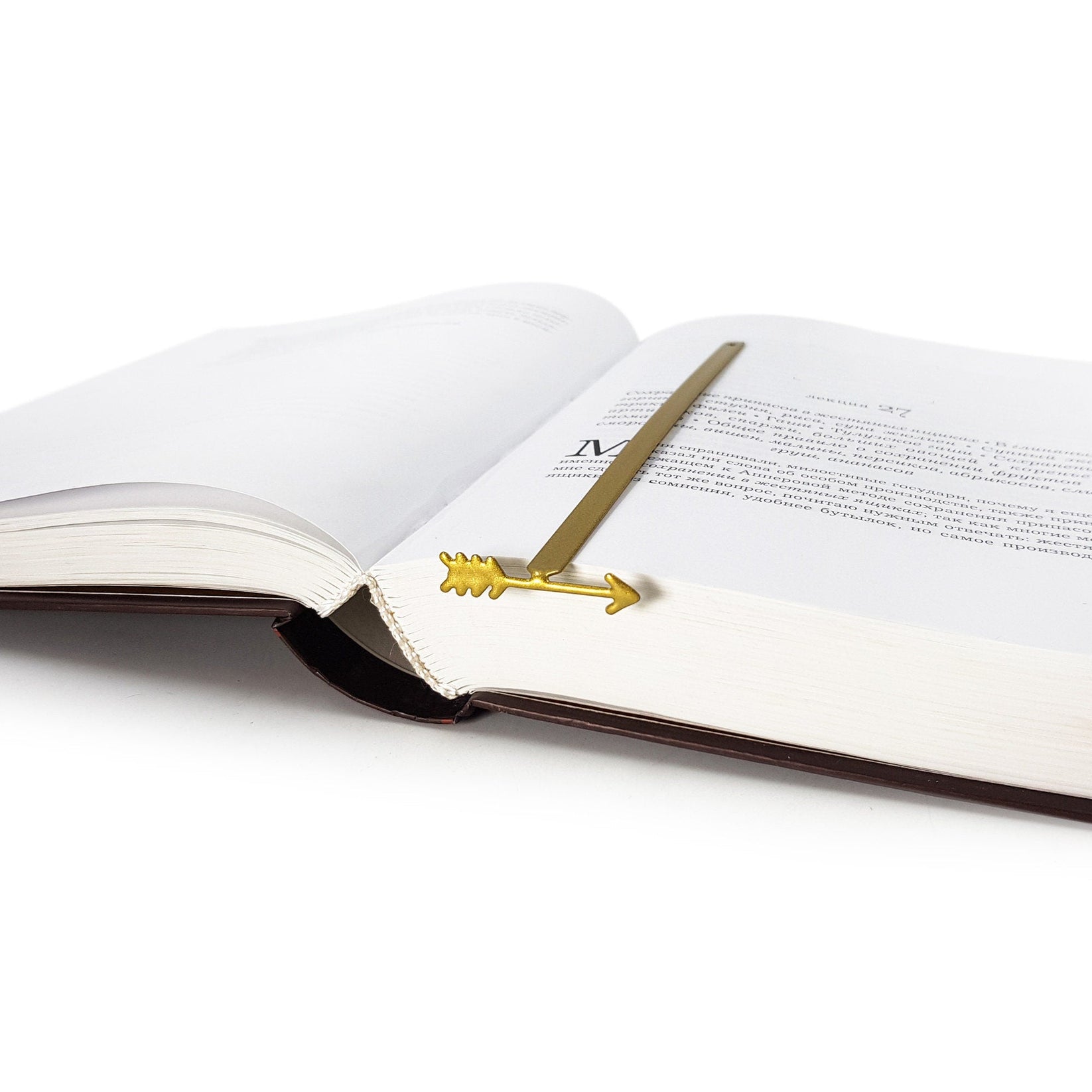 Arrow metal bookmark in gold marking a page in an open book